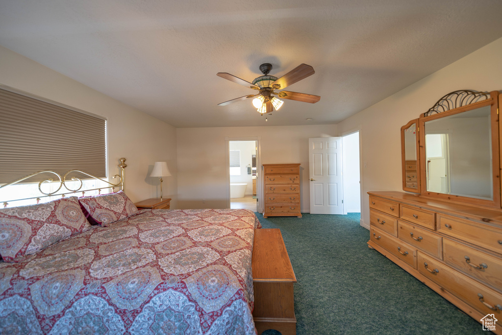 Bedroom with dark colored carpet, ceiling fan, and ensuite bathroom