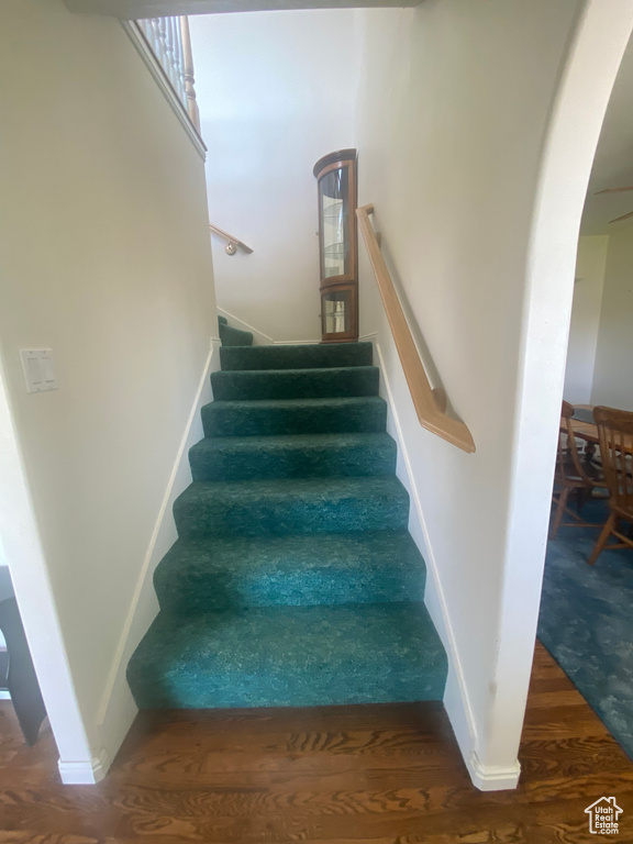 Stairs featuring arched walkways and wood finished floors