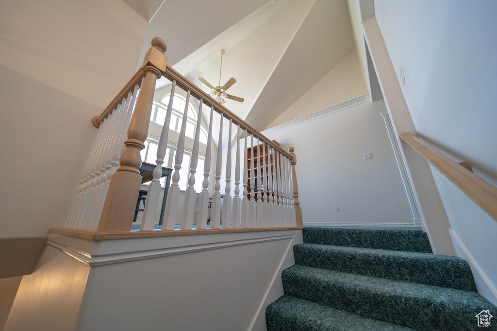 Stairs with ceiling fan and high vaulted ceiling