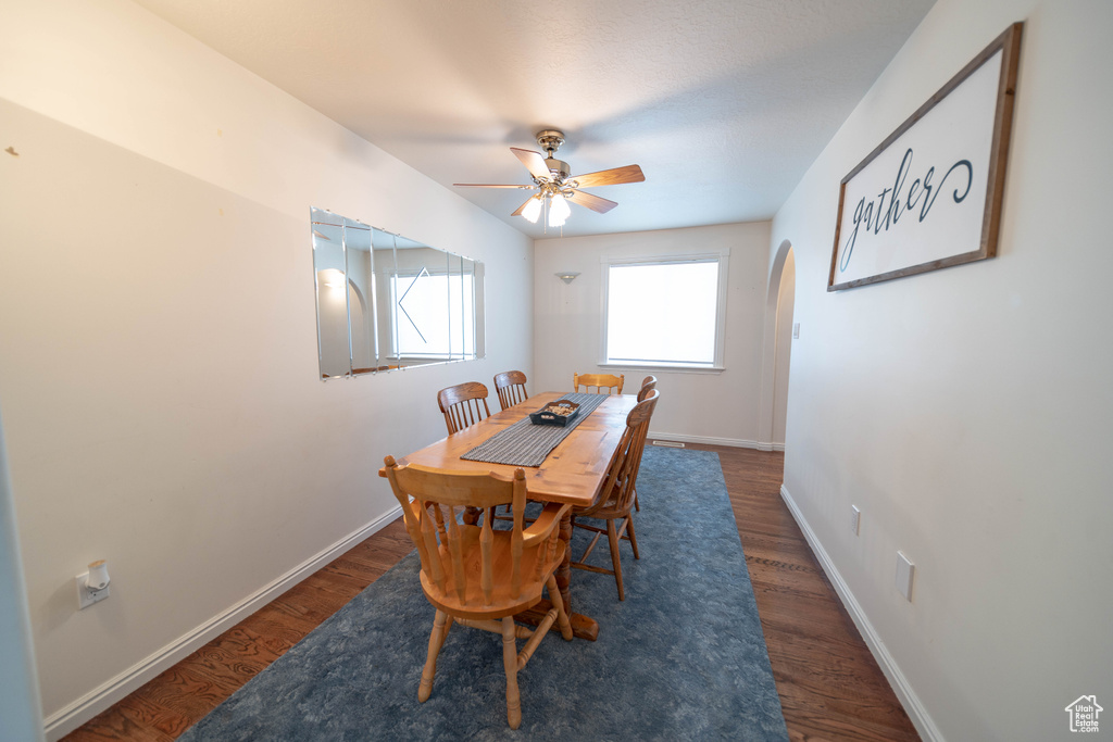 Dining area with arched walkways, wood finished floors, and a ceiling fan