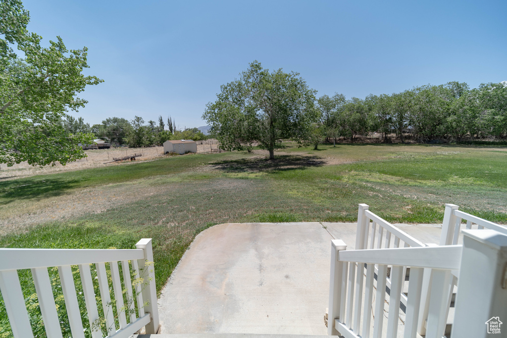 View of green lawn featuring a patio and a rural view