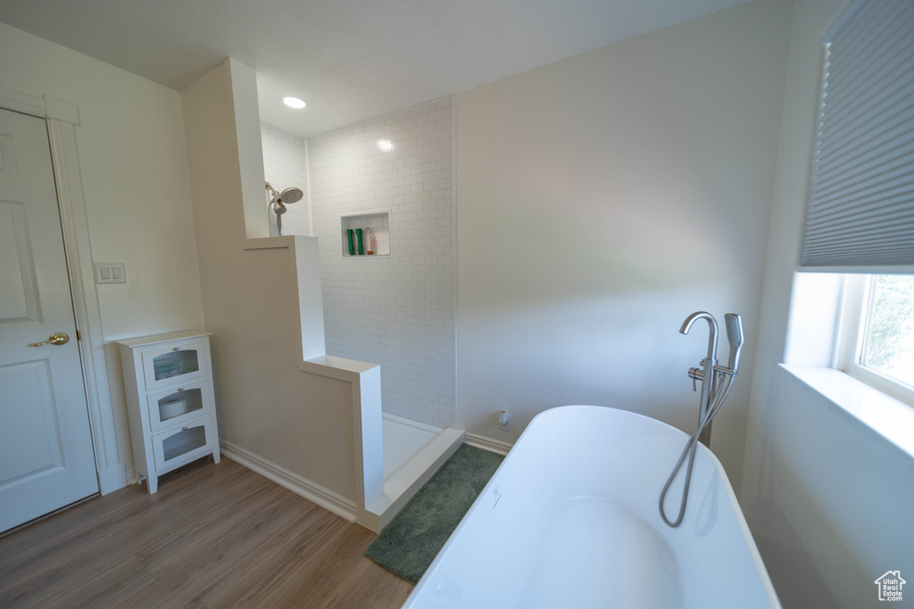 Full bath with wood finished floors, tiled shower, a freestanding bath, and recessed lighting