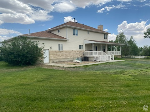Rear view of house with a chimney, a yard, and covered porch