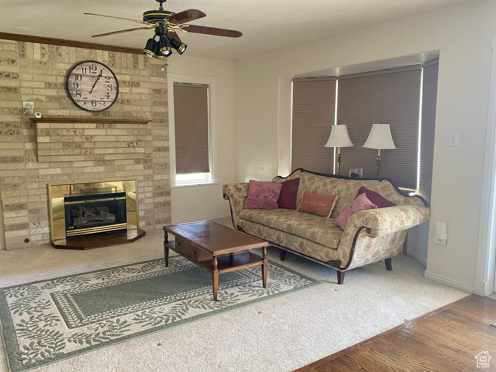 Living room featuring ceiling fan, wood finished floors, a brick fireplace, and carpet