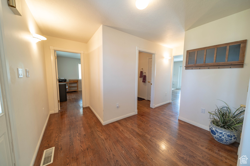 Corridor featuring dark wood-style flooring and baseboards