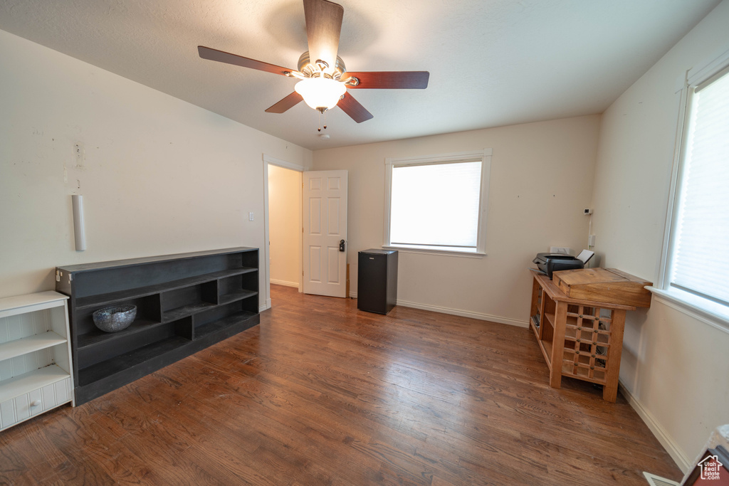 Unfurnished living room with a ceiling fan, wood finished floors, and plenty of natural light
