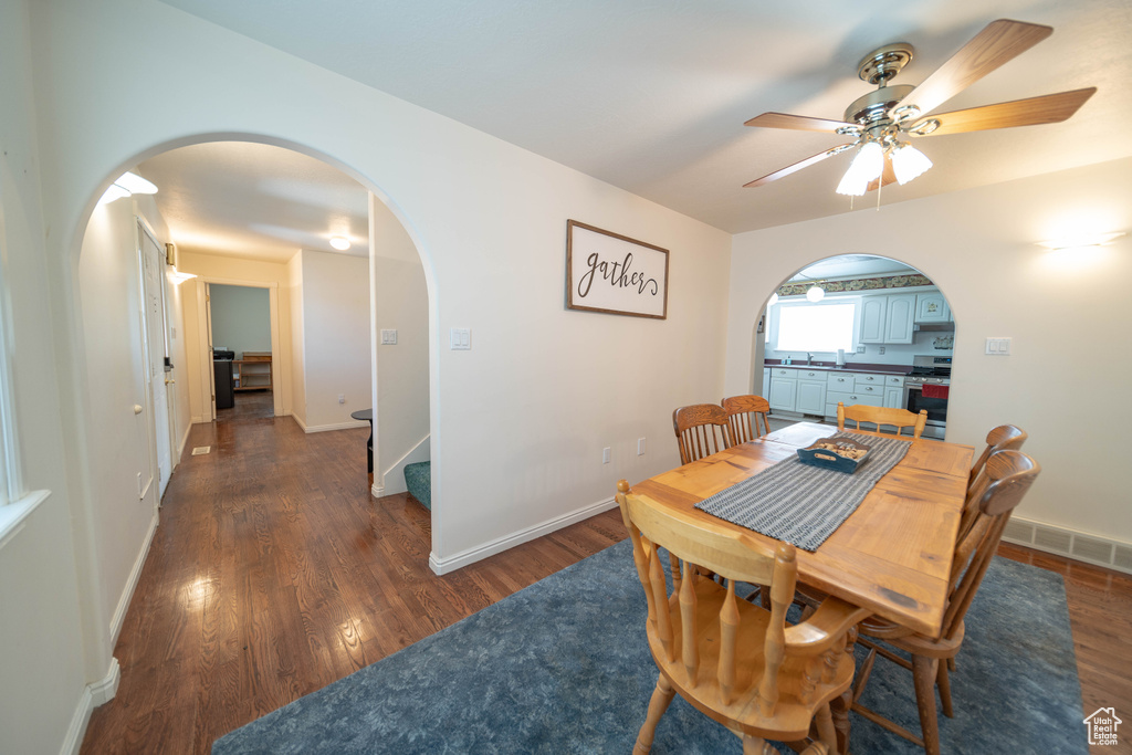 Dining area featuring arched walkways, wood finished floors, ceiling fan, and stairs