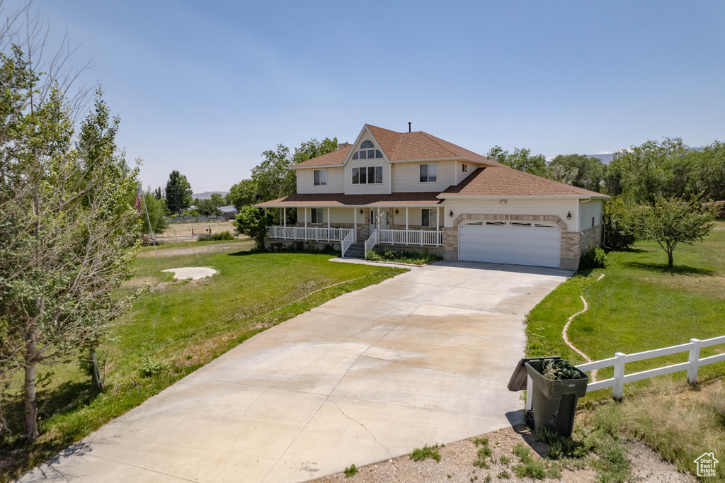 View of front of property with a porch, a garage, concrete driveway, stone siding, and a shingled roof