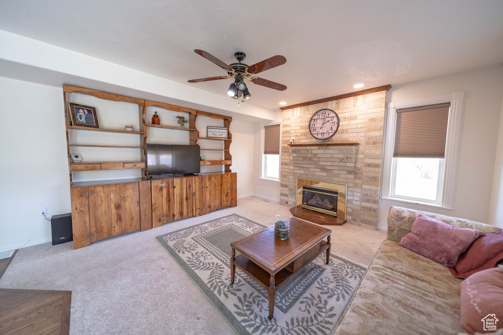 Carpeted living area with ceiling fan, a brick fireplace, and recessed lighting