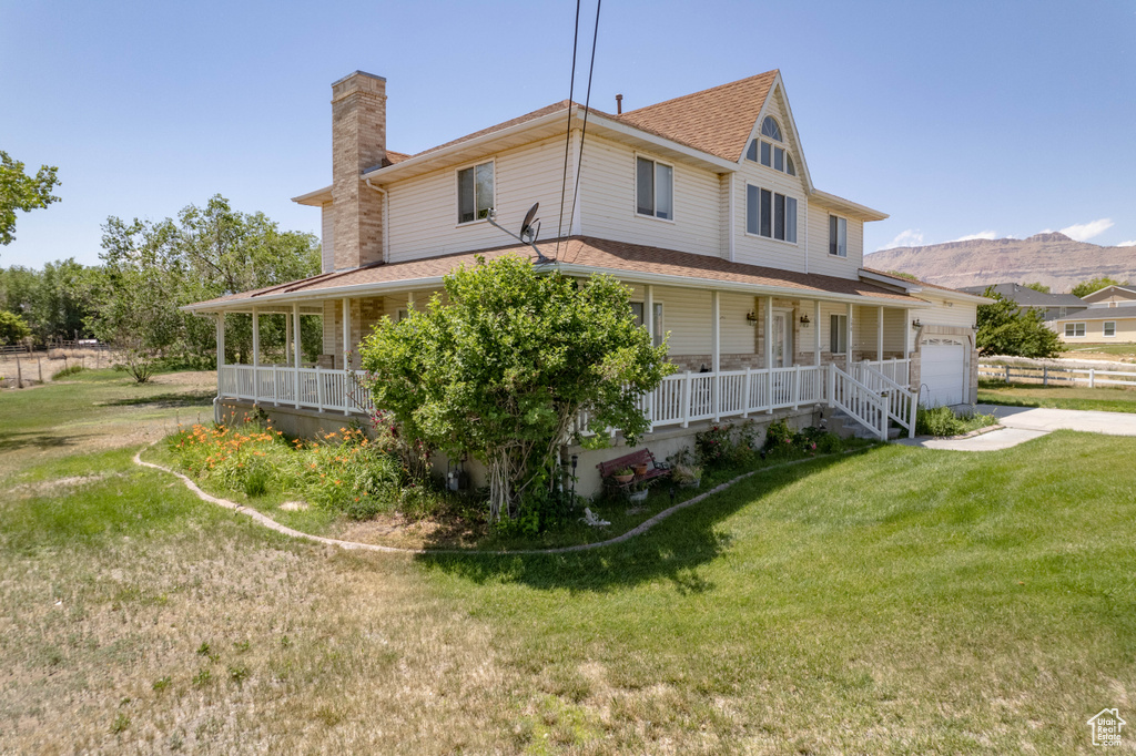 View of property exterior with a porch, a chimney, a garage, roof with shingles, and a yard