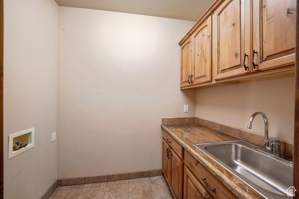 Laundry area with hookup for a washing machine, cabinet space, and light tile patterned floors