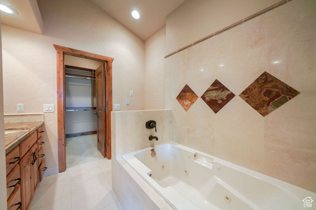 Bathroom with a whirlpool tub, vanity, tile patterned flooring, and recessed lighting