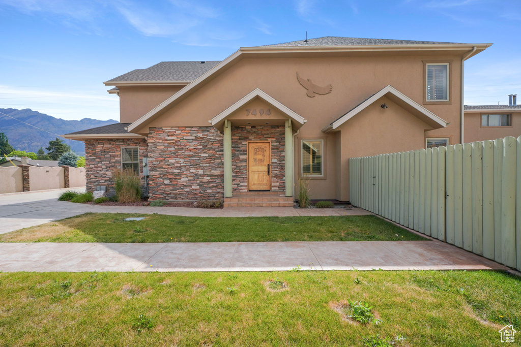 View of front facade featuring stucco siding, a mountain view, a gate, and stone siding