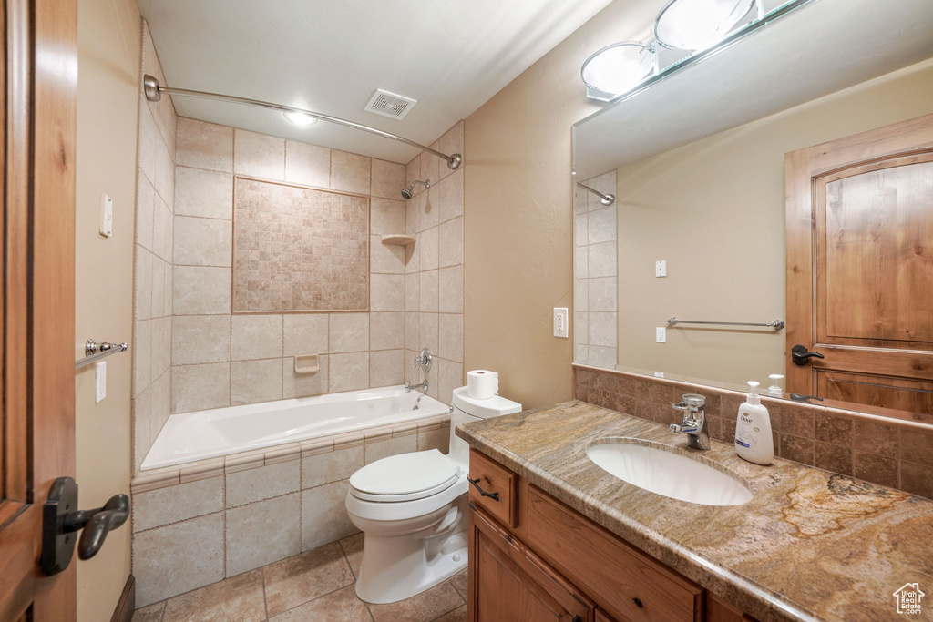 Bathroom featuring tiled shower / bath combo, vanity, tile patterned floors, and decorative backsplash