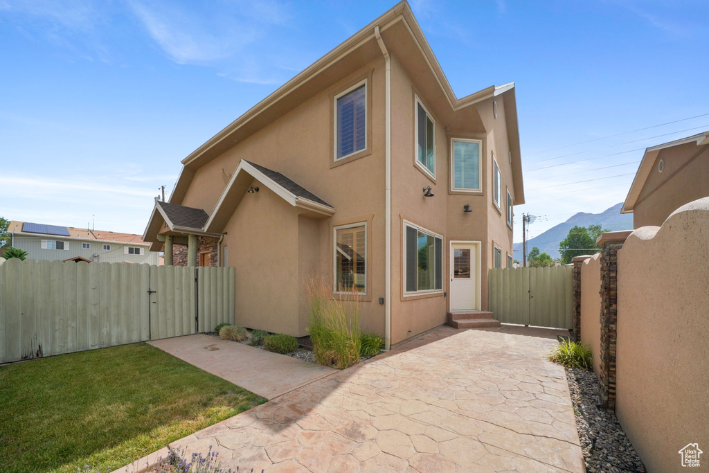 Rear view of property with a gate, stucco siding, a patio area, and a mountain view