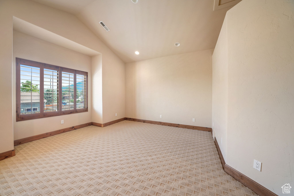Empty room with lofted ceiling, recessed lighting, and light carpet