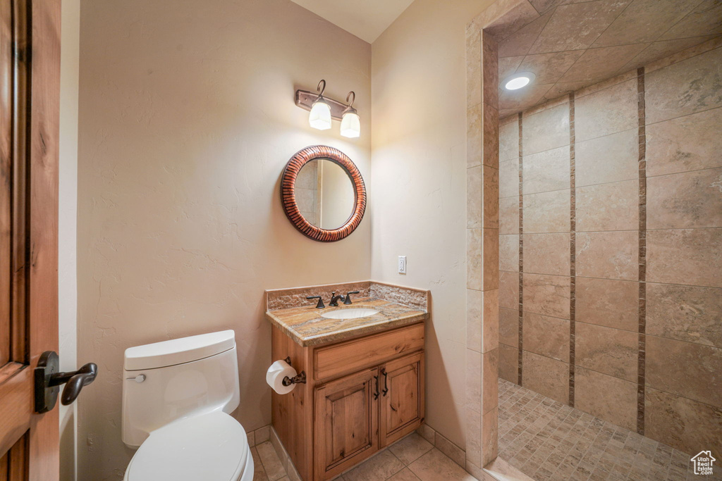 Full bathroom featuring vanity, a tile shower, and tile patterned flooring