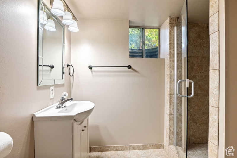 Full bathroom with vanity, a shower stall, and tile patterned floors