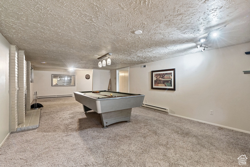 Rec room with a baseboard radiator, carpet, billiards, and a textured ceiling