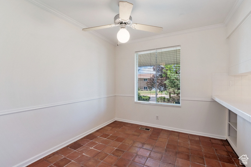 Unfurnished room with crown molding, dark tile patterned floors, and ceiling fan
