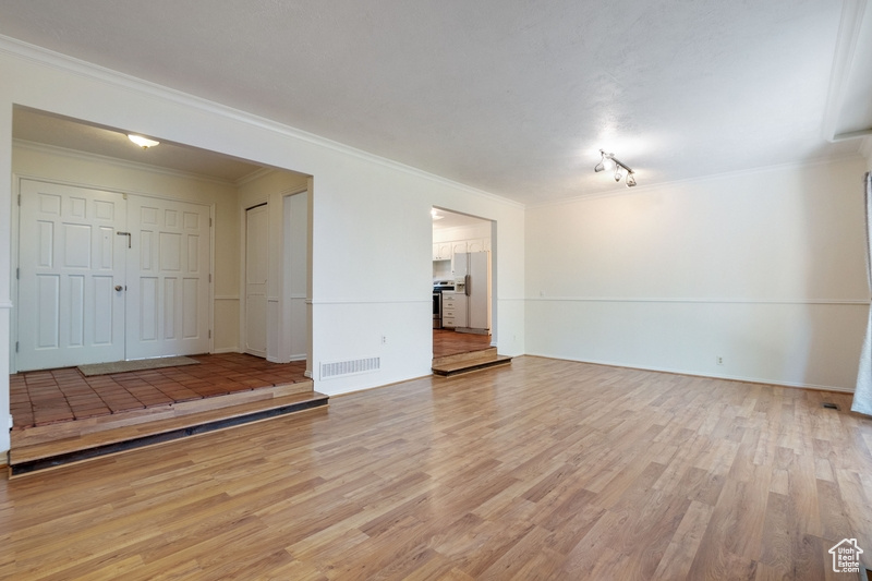 Unfurnished living room with light wood finished floors and crown molding