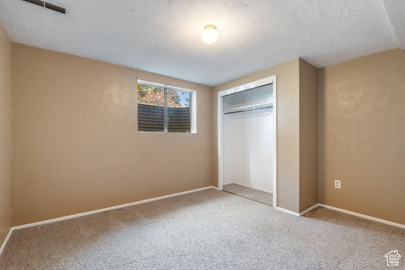 Unfurnished bedroom featuring a textured ceiling, carpet, and a closet