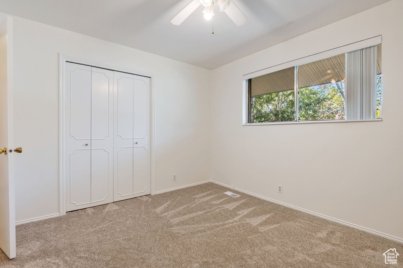 Unfurnished bedroom with carpet flooring, a closet, and ceiling fan
