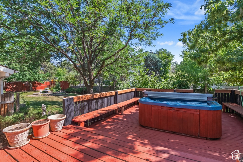 Wooden terrace featuring a hot tub and a fenced backyard