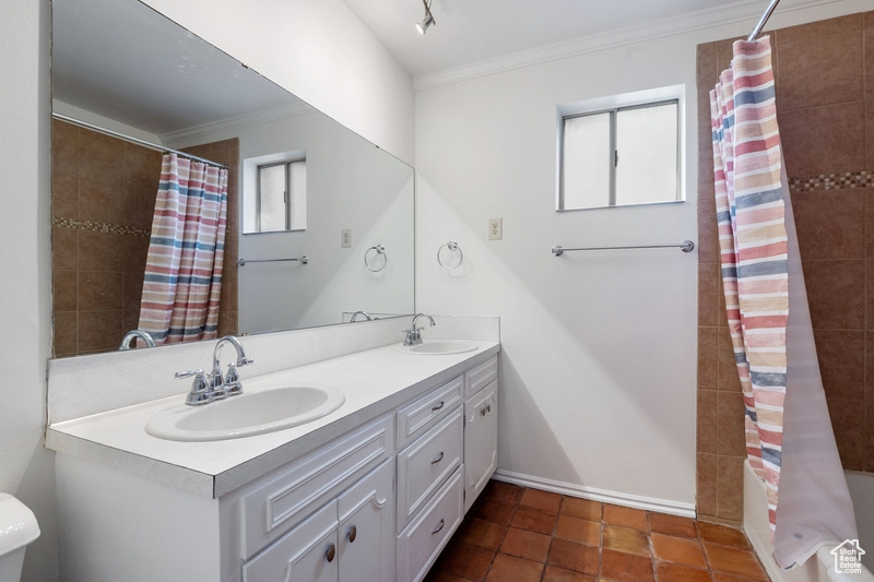 Bathroom with double vanity, ornamental molding, curtained shower, healthy amount of natural light, and tile patterned flooring