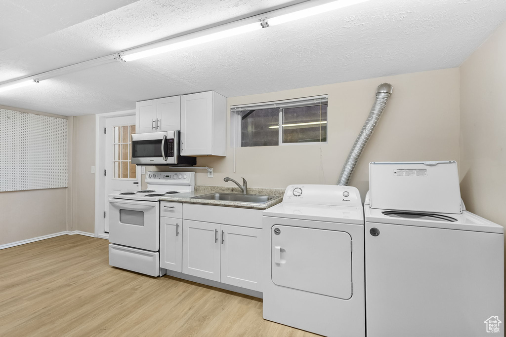 Washroom featuring independent washer and dryer, light wood-style flooring, and a textured ceiling
