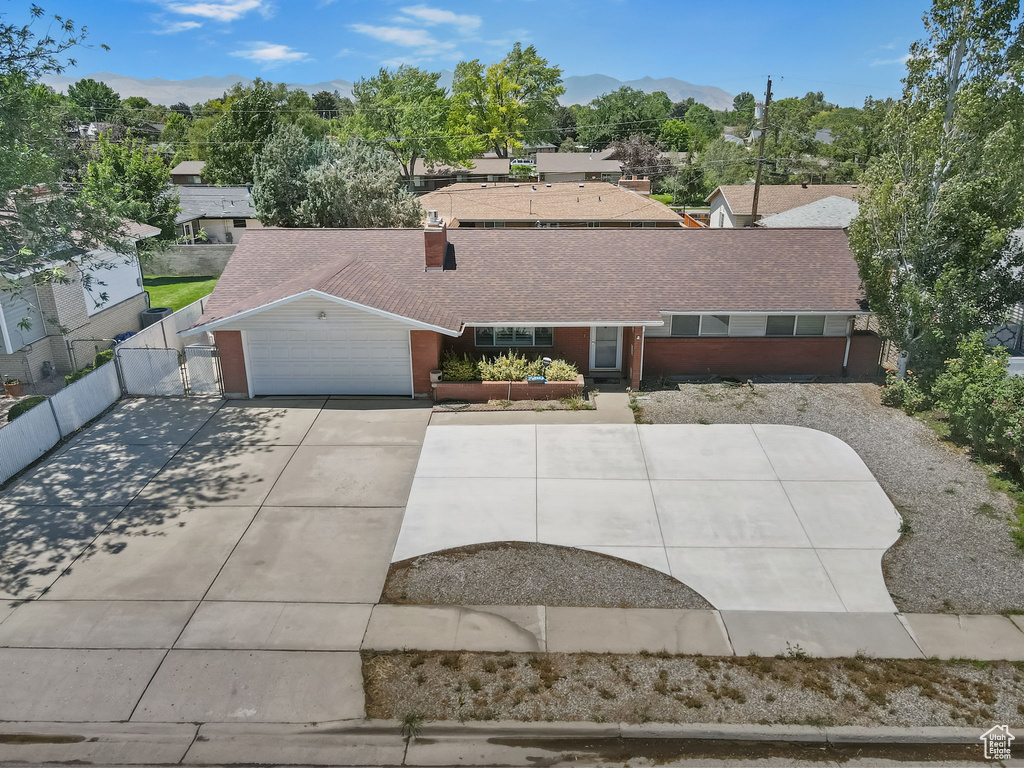 Single story home featuring roof with shingles, a garage, a mountain view, and driveway