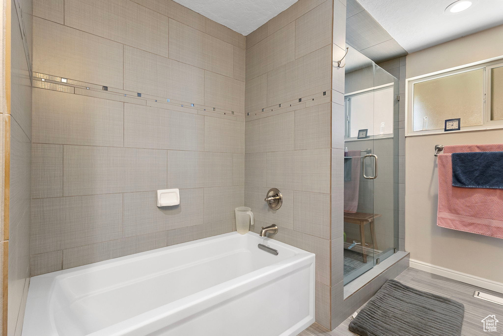 Bathroom with a stall shower, a bath, recessed lighting, and wood finished floors