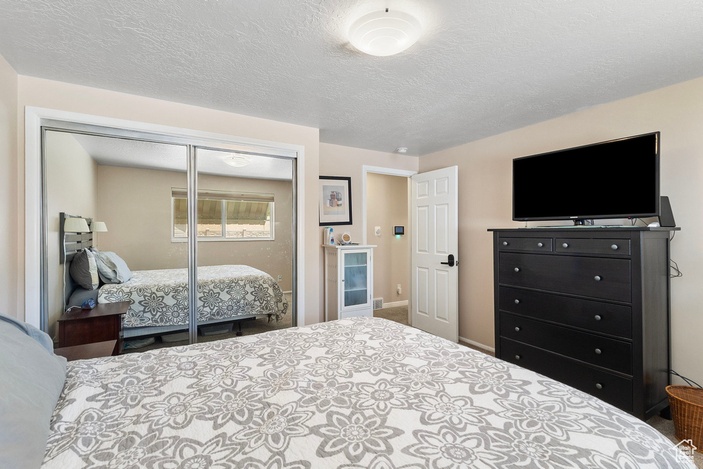 Carpeted bedroom with a closet and a textured ceiling