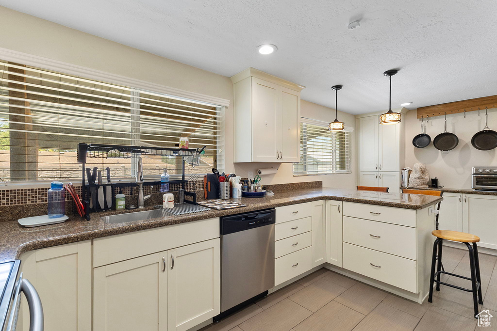 Kitchen featuring stainless steel dishwasher, a peninsula, decorative light fixtures, range, and recessed lighting