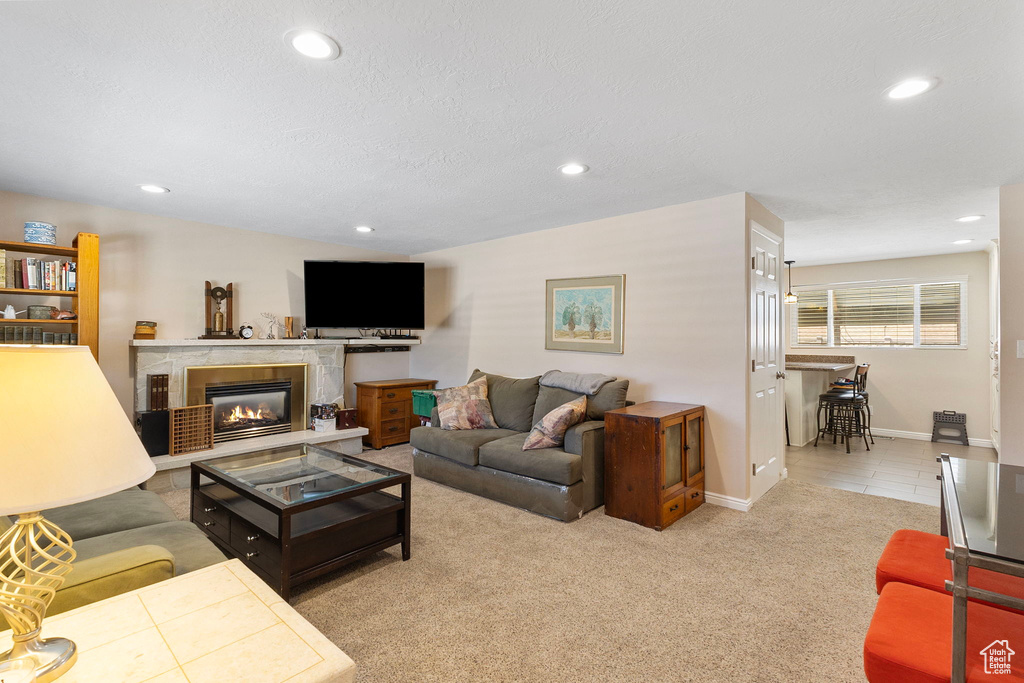 Living area with recessed lighting, a glass covered fireplace, and carpet floors
