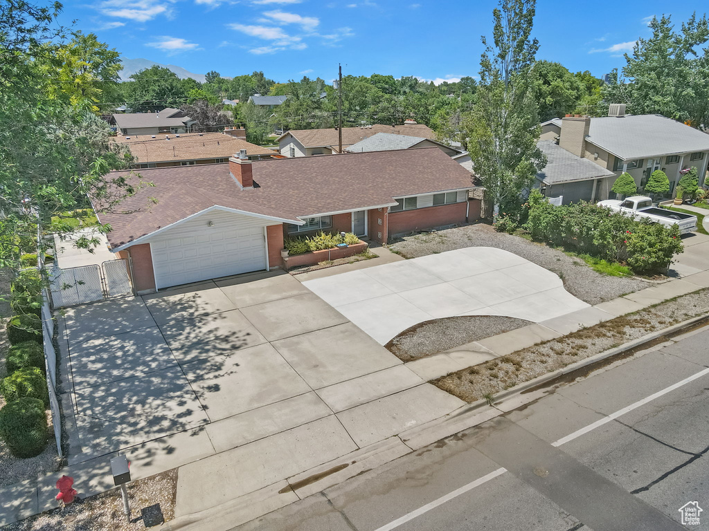Ranch-style home with concrete driveway, a gate, a residential view, and roof with shingles