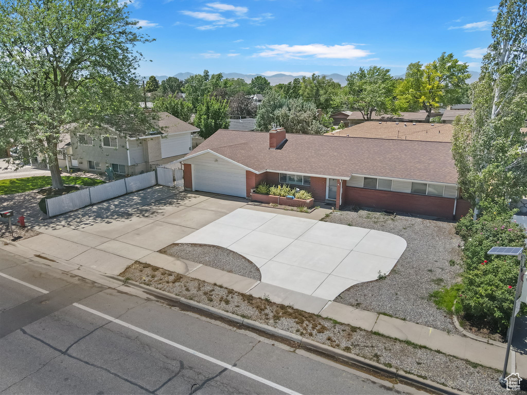 Ranch-style house featuring a chimney, a mountain view, driveway, a garage, and a shingled roof