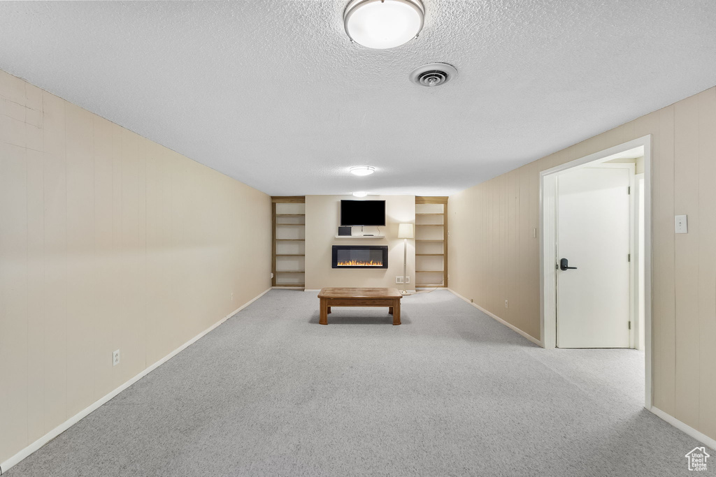 Playroom featuring a glass covered fireplace, a textured ceiling, carpet, and built in shelves