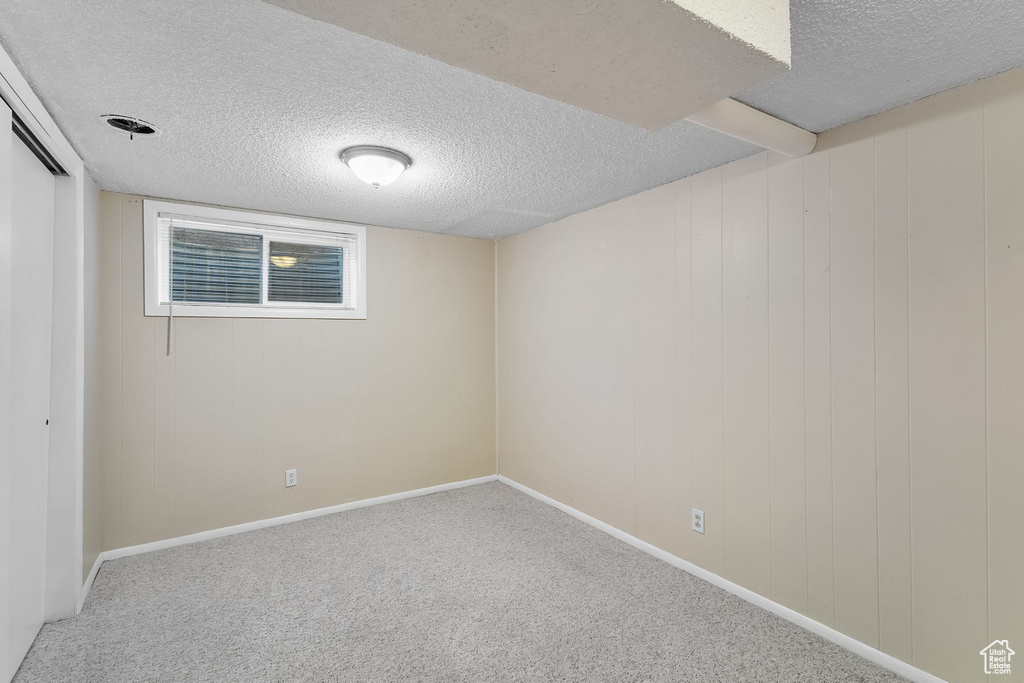 Finished basement with a textured ceiling and carpet