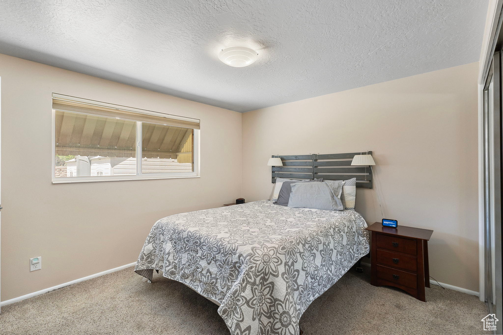 Carpeted bedroom with baseboards and a textured ceiling