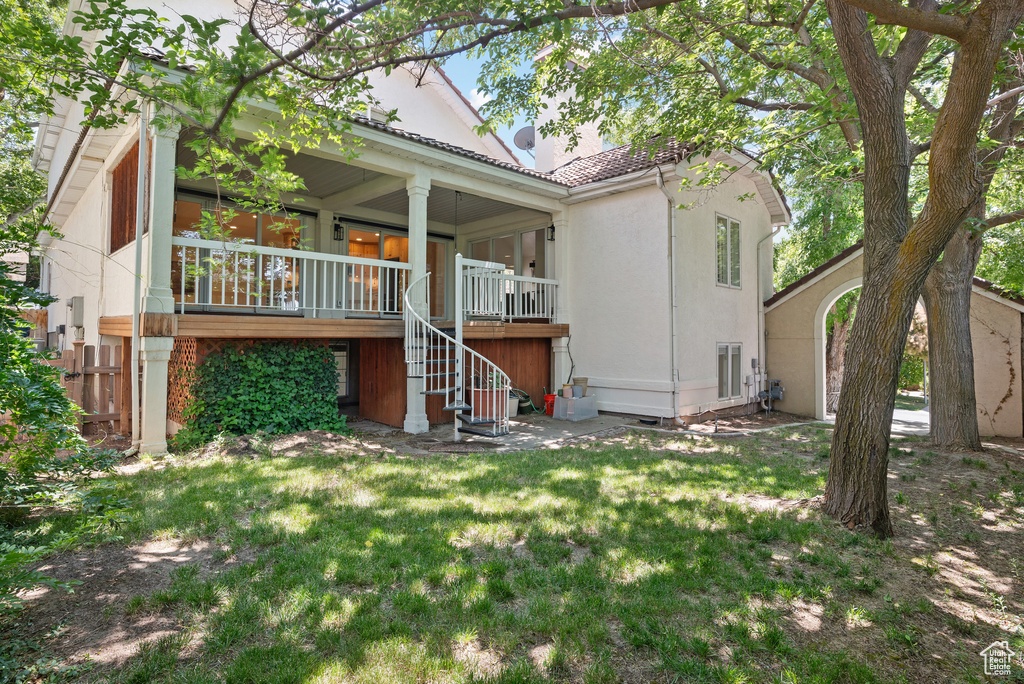 Rear view of house featuring stairs, covered porch, a lawn, a tiled roof, and stucco siding