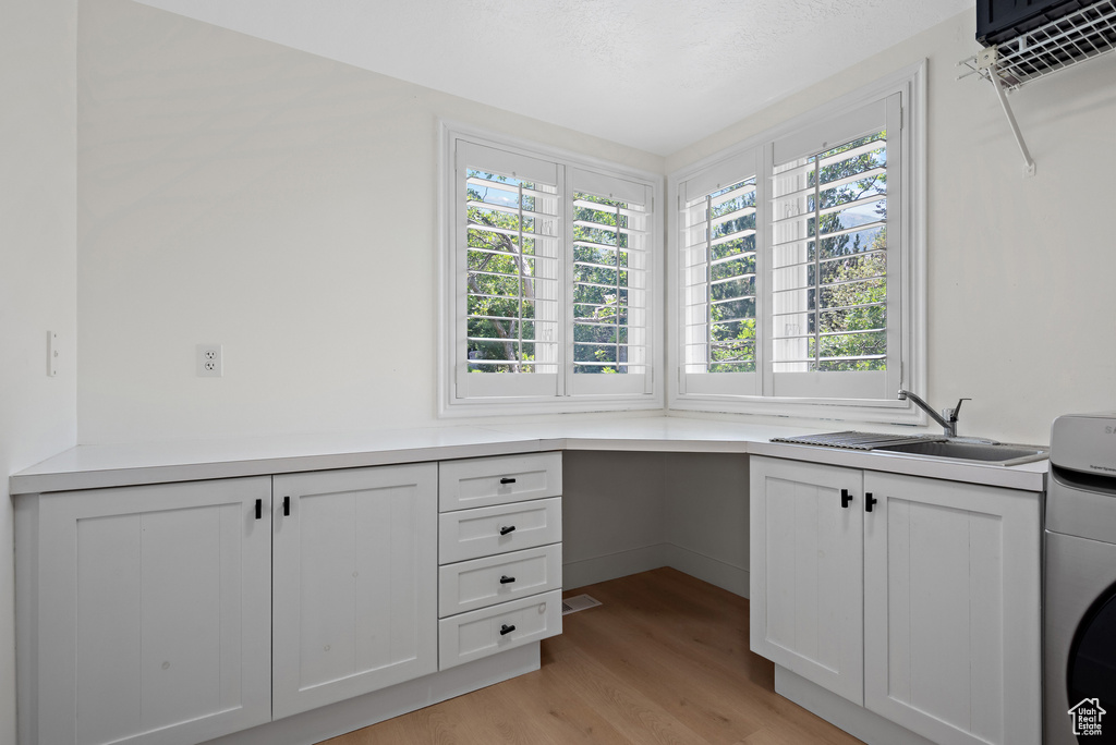 Unfurnished office with washer / dryer, healthy amount of natural light, and light wood-style flooring