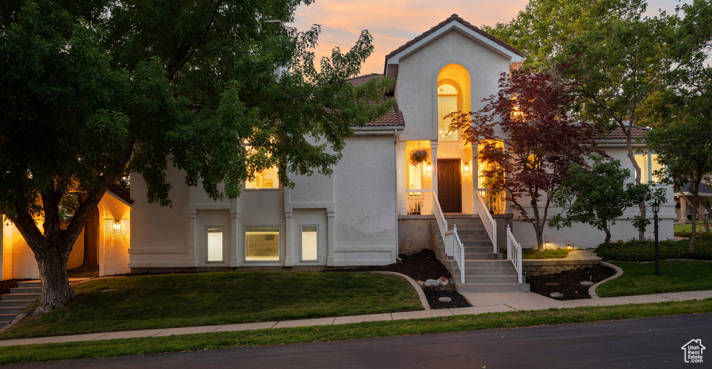 Mediterranean / spanish house featuring stucco siding, a lawn, and a tile roof