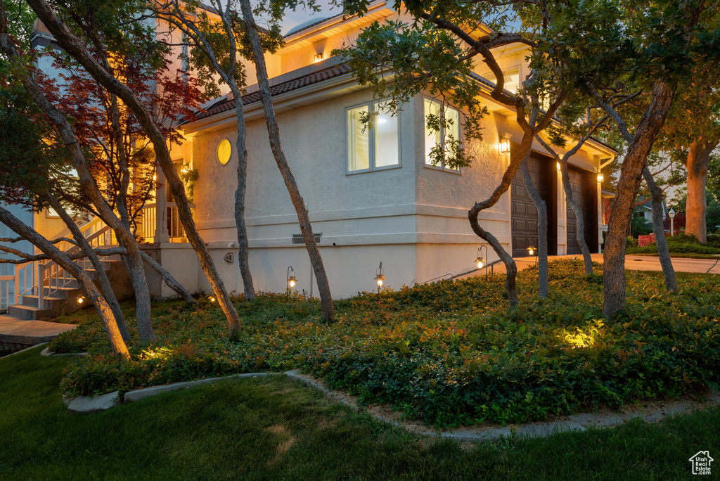 View of property exterior featuring driveway, stucco siding, and a lawn