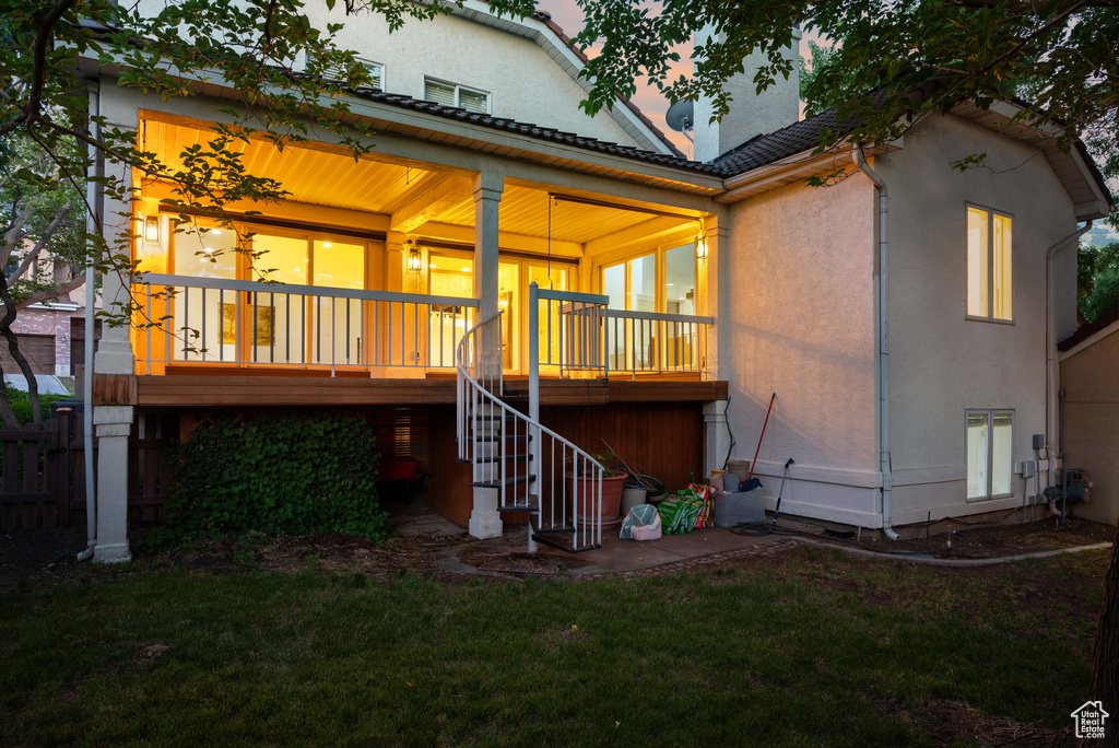 Rear view of house featuring stairs, a lawn, covered porch, and stucco siding