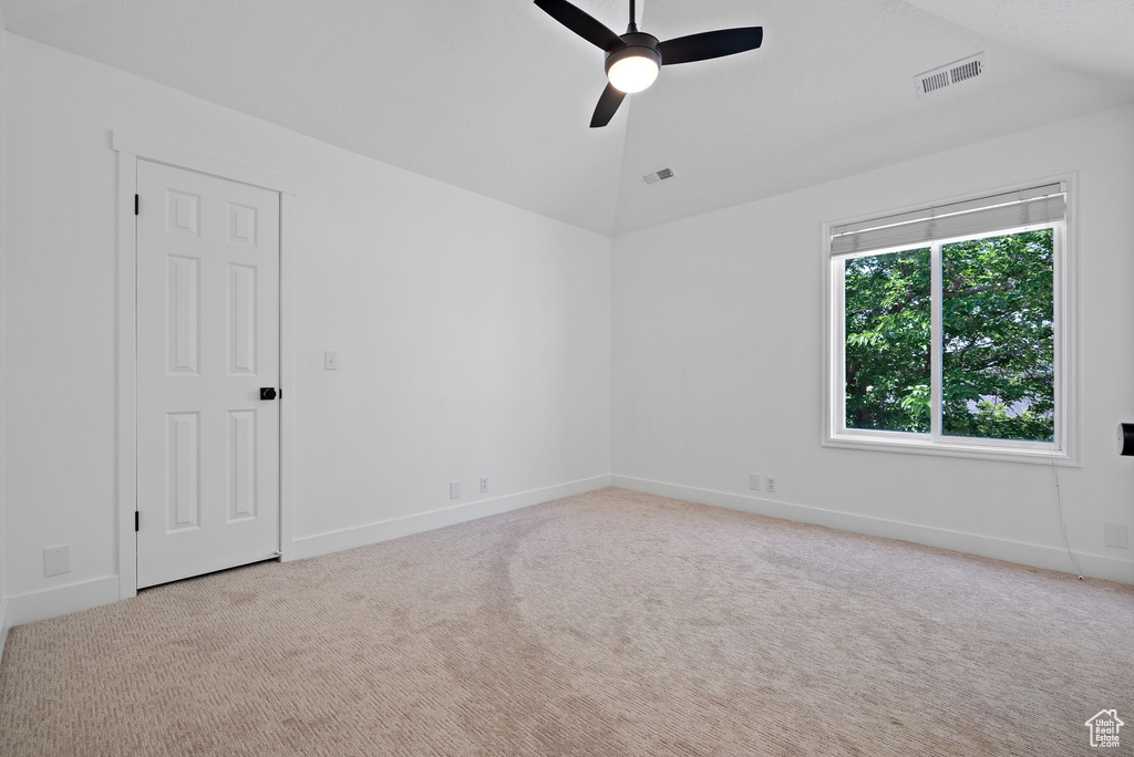 Carpeted spare room with ceiling fan and vaulted ceiling