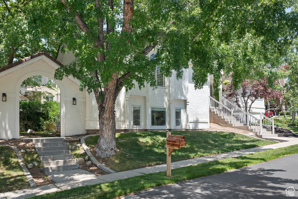View of front of home with stairway, stucco siding, and a front lawn
