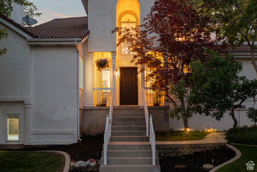 View of exterior entry with stucco siding and a tile roof