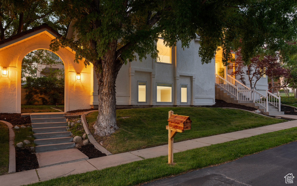 View of front of home featuring stairs, stucco siding, and a front lawn