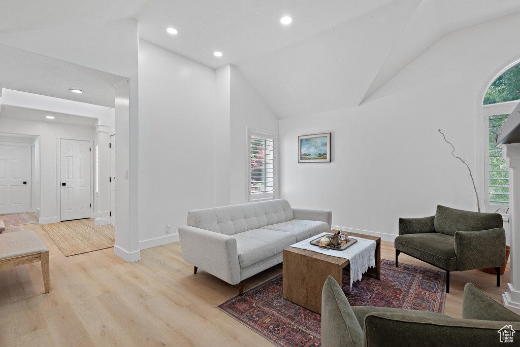 Living area with healthy amount of natural light, light wood-style flooring, high vaulted ceiling, and recessed lighting